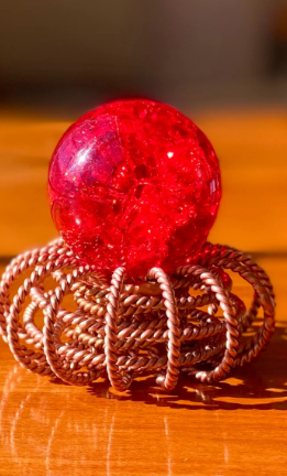 Red crystal ball on a metallic stand with a blurred background