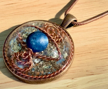 Pendant with blue sphere and copper wire design on a wooden surface