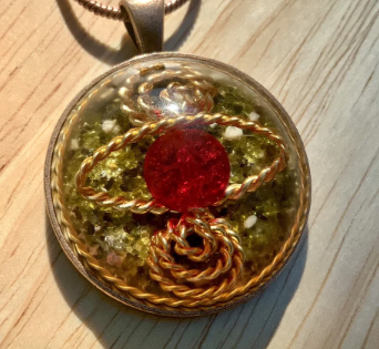 Gold pendant with a red stone on a wooden surface