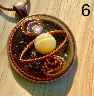 Decorative pendant with a central sphere and braided design on a wooden surface