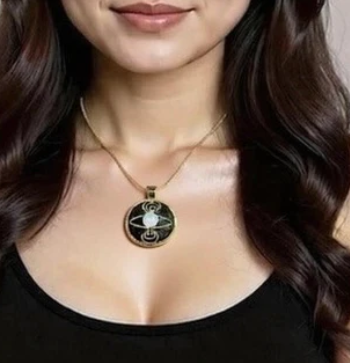 Close-up of a necklace with a pendant worn by a person with long, wavy hair.