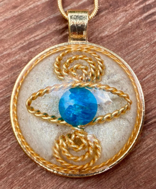 Gold pendant with a blue gemstone on a wooden surface