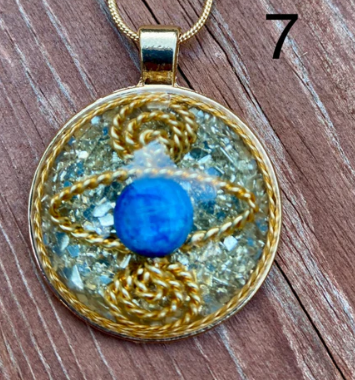 Gold pendant with a blue stone on a wooden surface