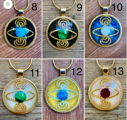 Set of six circular pendants with gold frames and colorful central stones on a wooden surface.