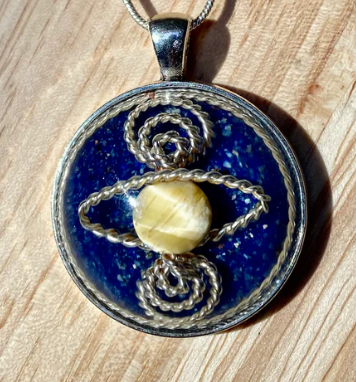 Pendant with blue stone and yellow bead on a wooden surface