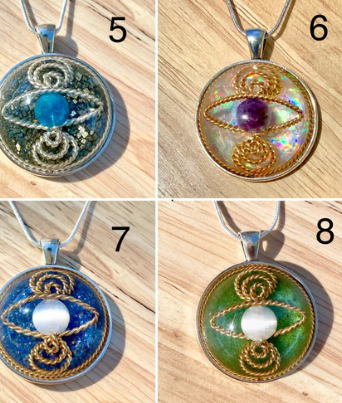 Four pendant necklaces with different designs on a wooden surface.