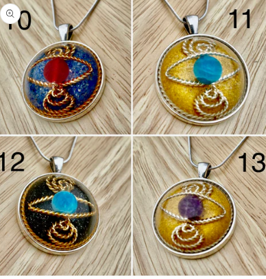 Four circular pendants with different colored stones on a wooden surface