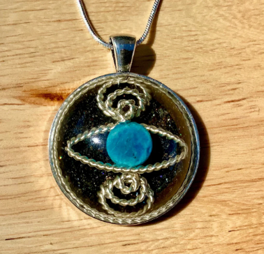 Pendant with blue stone and silver design on a wooden surface