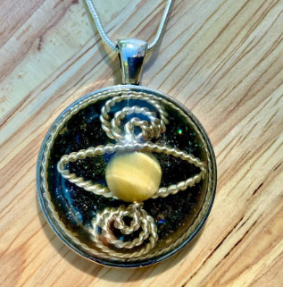 Round pendant with spiral design and yellow center on a wooden surface