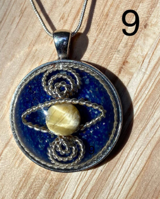 Pendant with blue stone and yellow center on a wooden surface