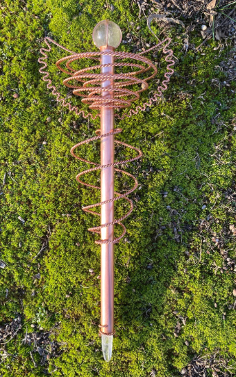 Copper spiral coiled wand with crystal on a green moss background