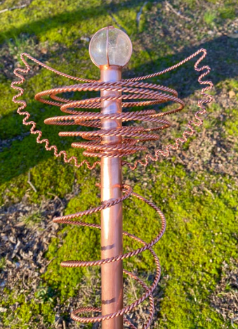 Copper decorative garden stake with a crystal ball on a grassy background