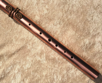 Copper flute on a textured beige surface