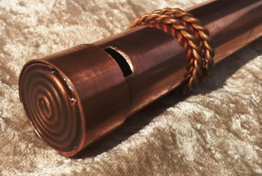 Copper-colored scroll with braided handle on a textured surface