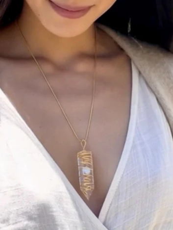 Necklace with a pendant worn by a person in a white top