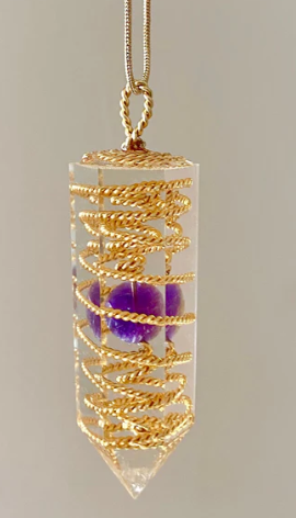 Gold crystal necklace with purple crystal on a gray background
