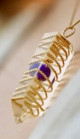 Gold necklace with a purple gemstone on a blurred background