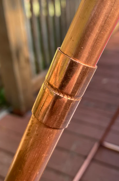Close-up of a copper pipe with a metallic sheen on a blurred background