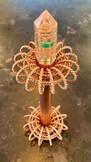 Decorative crystal with intricate copper base on a reflective surface
