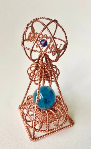 Copper wire sculpture with a blue sphere on a white background