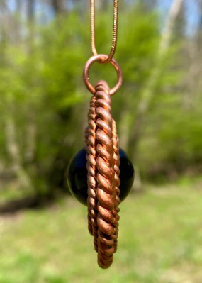 Copper pendant necklace with a blurred natural background