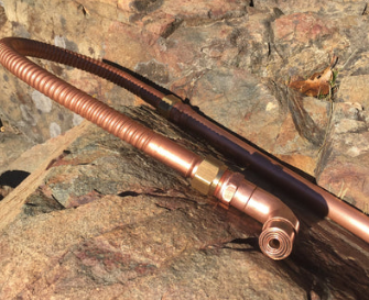 Copper hose with brass fittings on a rocky surface