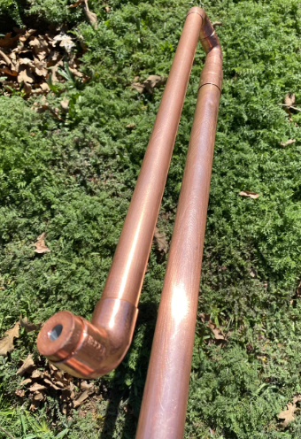 Copper pipe against a green leafy background