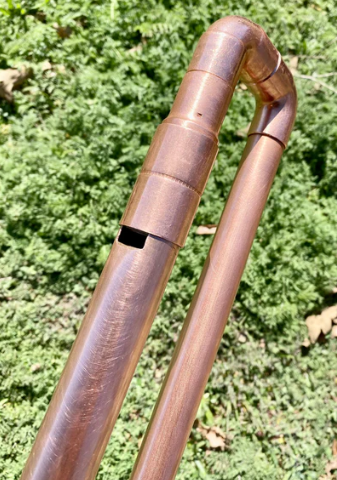 Copper pipe with a check valve against a green leafy background