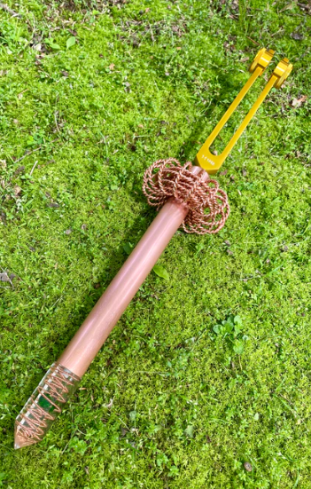 Metal tool with a yellow handle on green grass