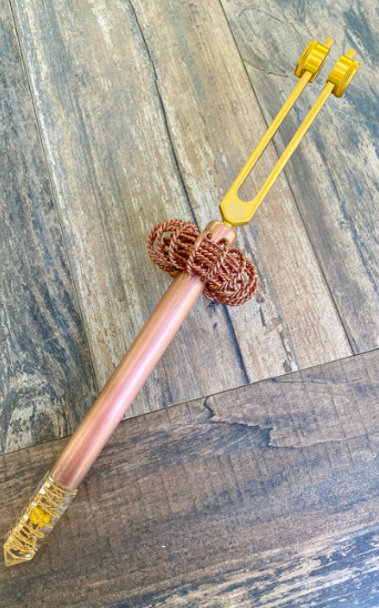 Decorative pen with a braided copper design on a wooden surface