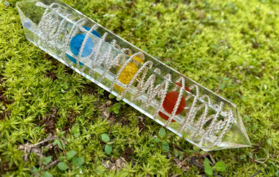 Transparent crystal with colorful embedded stones on a green moss background